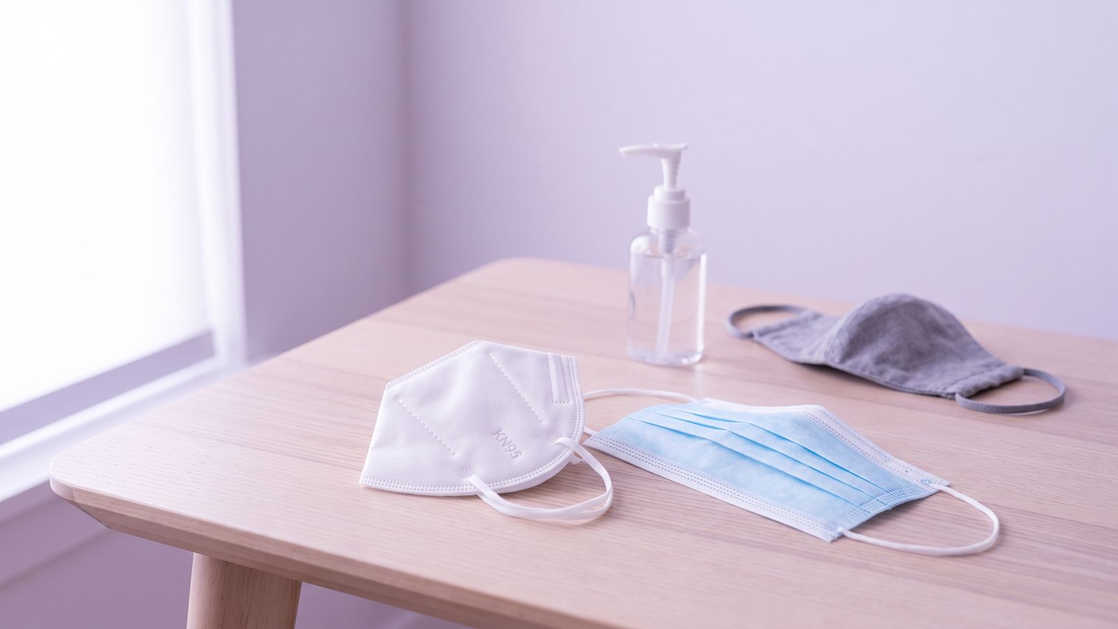 Mascarilla KN95, mascarilla quirúrgica y alcohol gel sobre una mesa