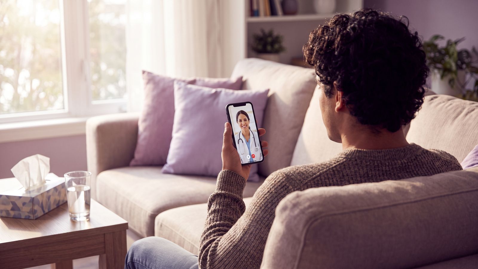 Hombre en su sillón en una videollamada con una doctora desde el celular