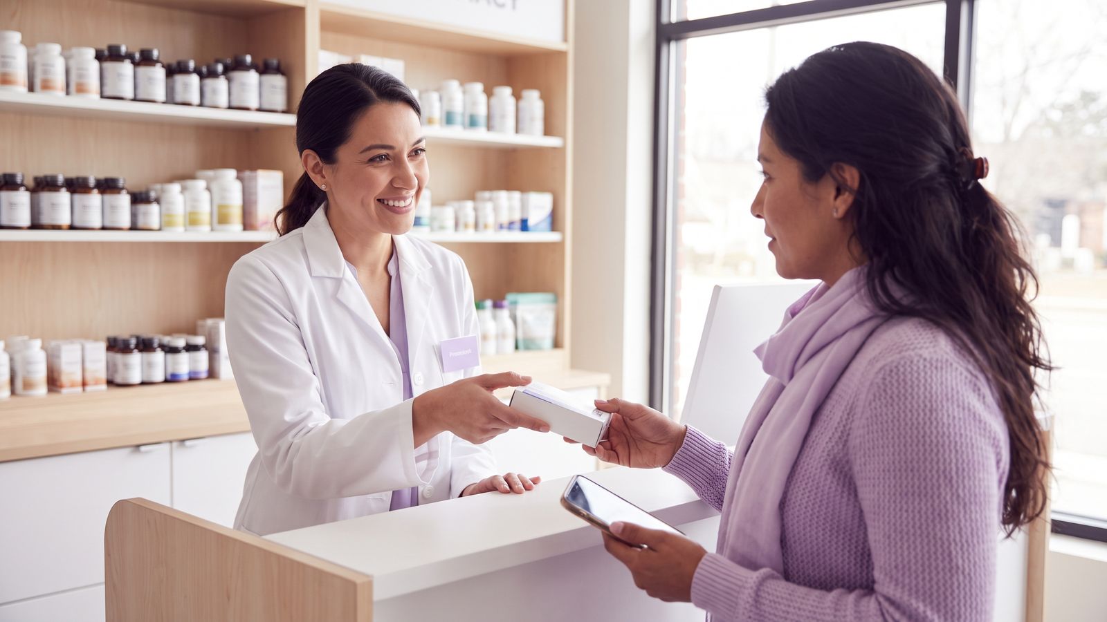 Farmacéutica entregando un medicamento a una paciente en la farmacia